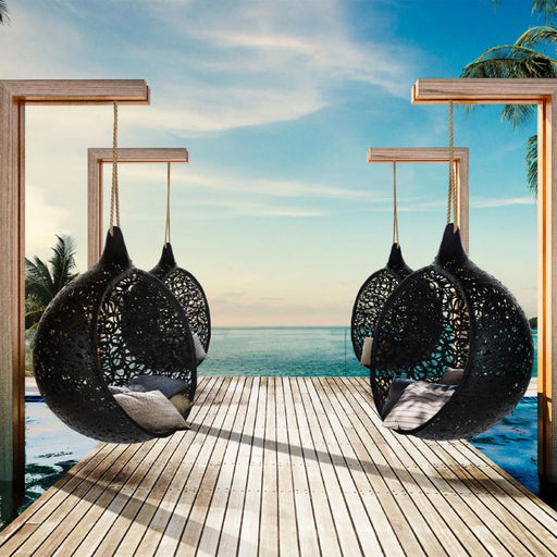 Zwarte hangstoelen bij een zwembad en de zee